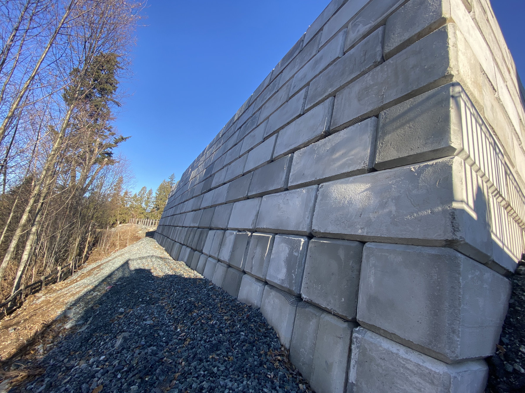 Long interlocking concrete block wall along a gravel path